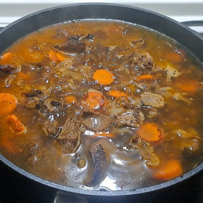Процесс первого тушения говядины с овощами и специями в сковороде