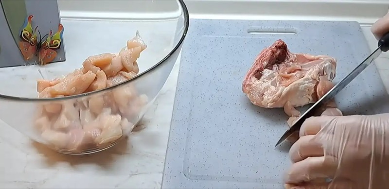 Нарезка куриного филе и мяса бедра кубиками на разделочной доске для домашнего террина