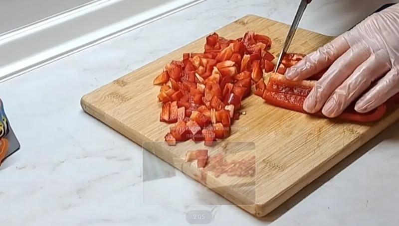 Добавление нарезанной красной паприки и целых оливок в миску с куриным фаршем.